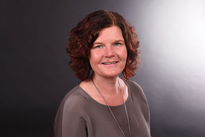 Nicole Götze - trägt ein braunes Oberteil. Sie hat lockige schulterlange Haare. Um den Hals trägt sie eine lange Kette. - Copyright: Fachdienst Ev. Kindertagesstätten